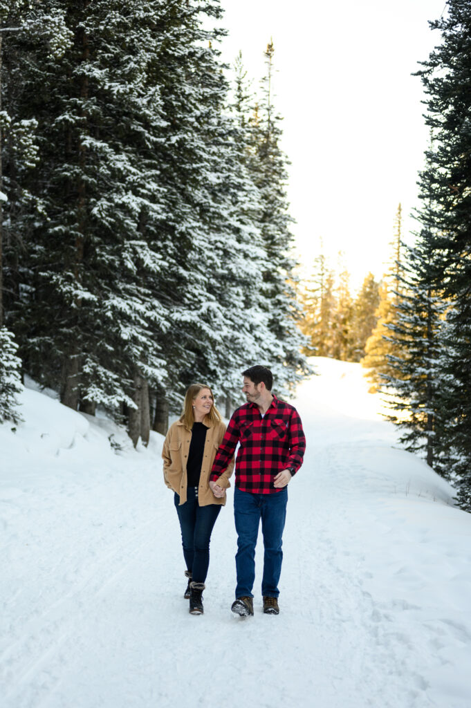 Couple walking down snowy pathway with trees