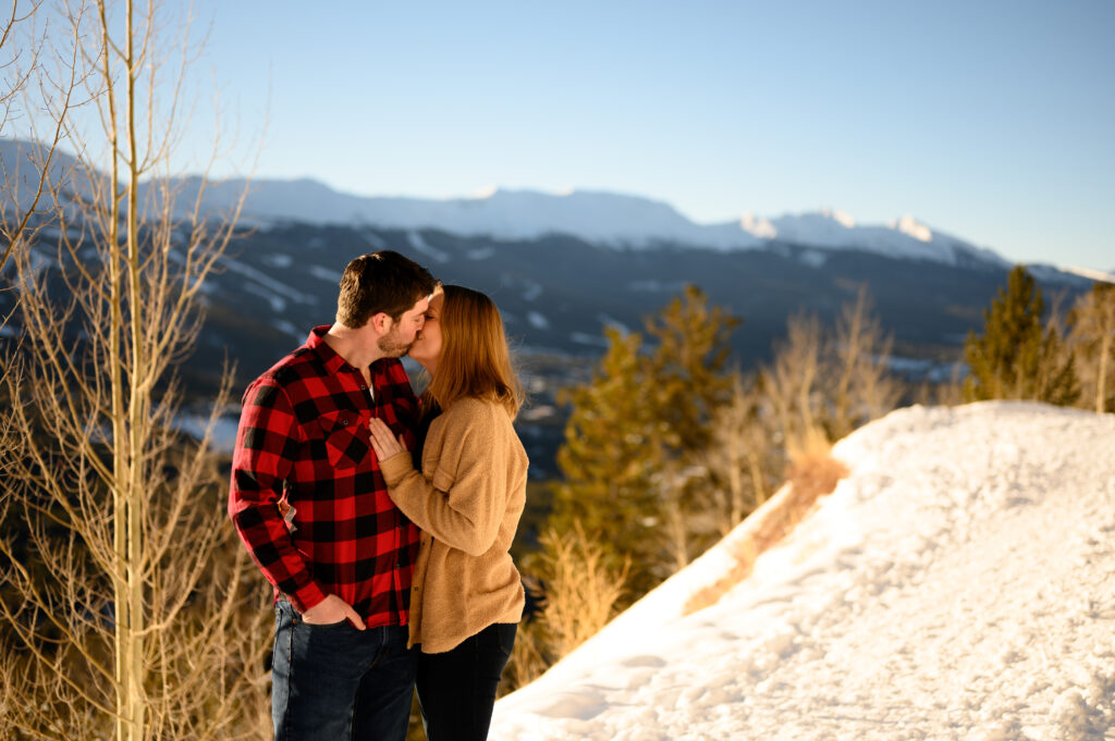 Couple kissing in front of snowy mountain