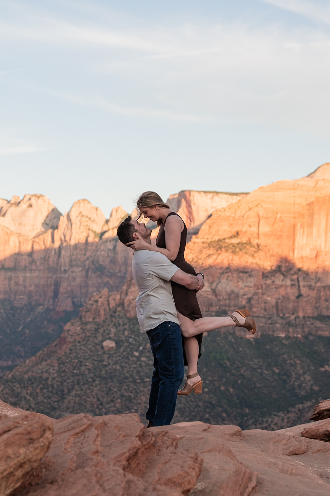 Engaged couple embracing in front of mountain range